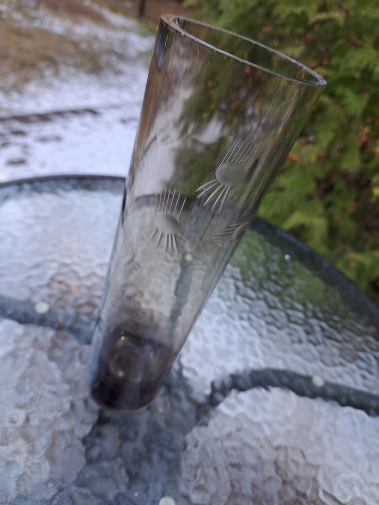 Brūngana (gaišāks tonis) cilindriskā stikla vāze ar smalku puķu grāvēšanu. Augstums 25,5cm, diam.7,5cm (Stikla vaze 151)