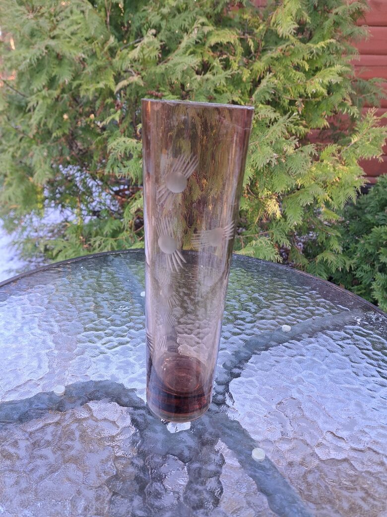 Brūngana (tumšāks tonis) cilindriskā stikla vāze ar smalku puķu grāvēšanu. Augstums 25,5cm, diam.7,5cm (Stikla vaze 150)