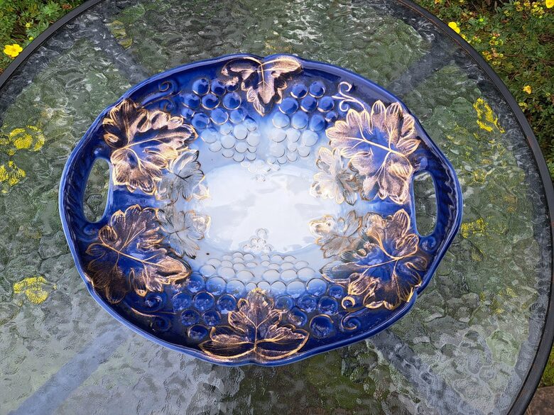 Grezna augļu bļoda ar reljefa rakstu - vīnogu ķekatiem, zilos toņos ar bagātīgu zeltu. Izmēri: 32cmx26,5cm (Korosten 66)