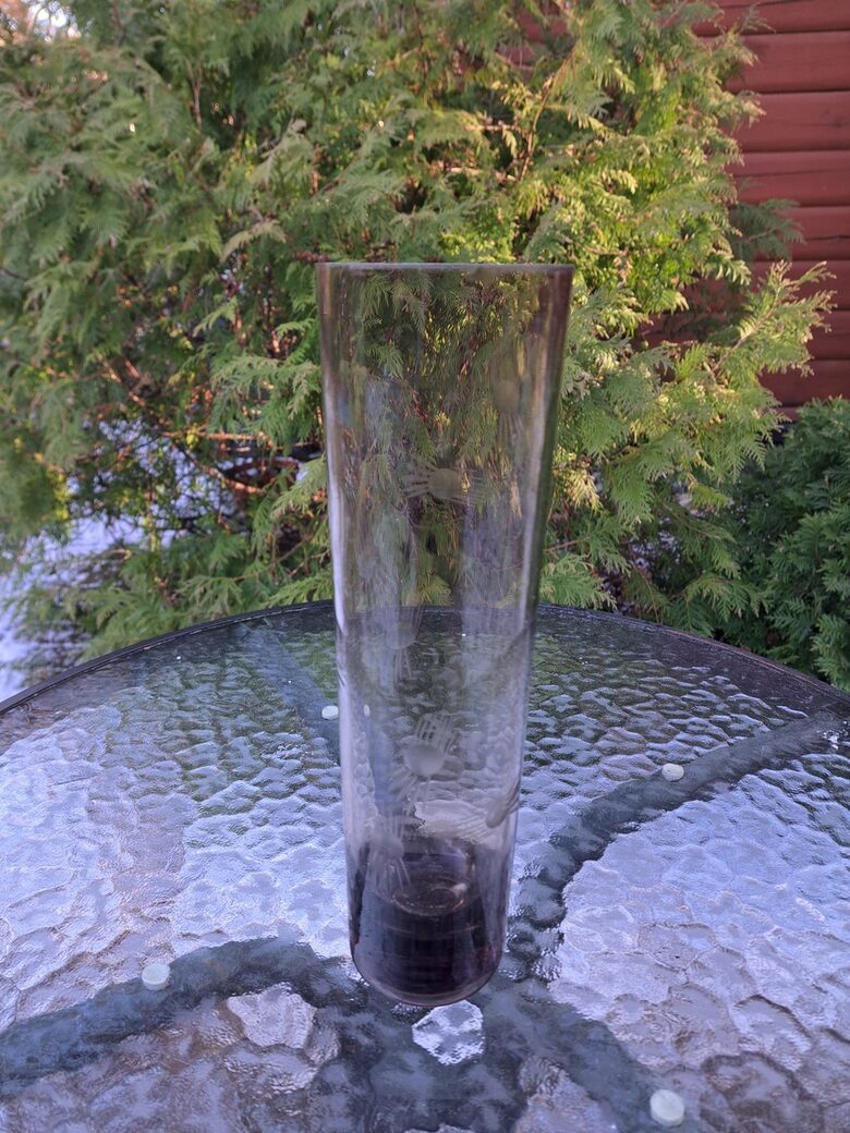 Brūngana (gaišāks tonis) cilindriskā stikla vāze ar smalku puķu grāvēšanu. Augstums 25,5cm, diam.7,5cm (Stikla vaze 151)