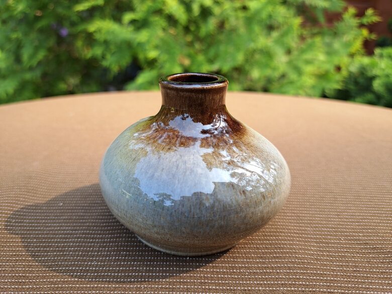 Māla vāzīte ar apaļa, plata ar šauru kakliņu, glazūra. Pelēcīgi brūna grāsa. Diam.7,5cm (Keram 152)