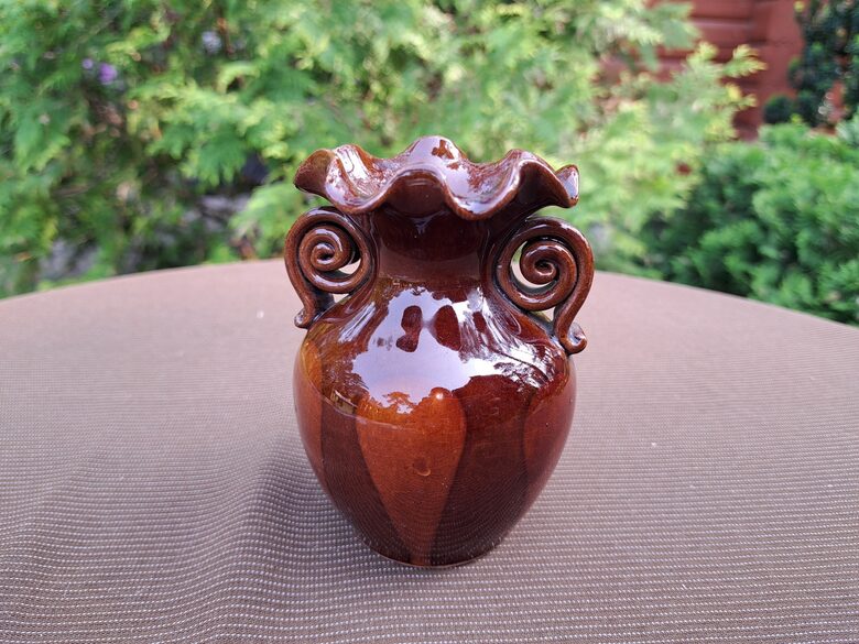 Māla vāzīte, viļņaina malas forma, brūna ar brūnu rakstu. Roku darbs, glazūra. Diam. 7cm. Augstums 11cm (Keram 142)