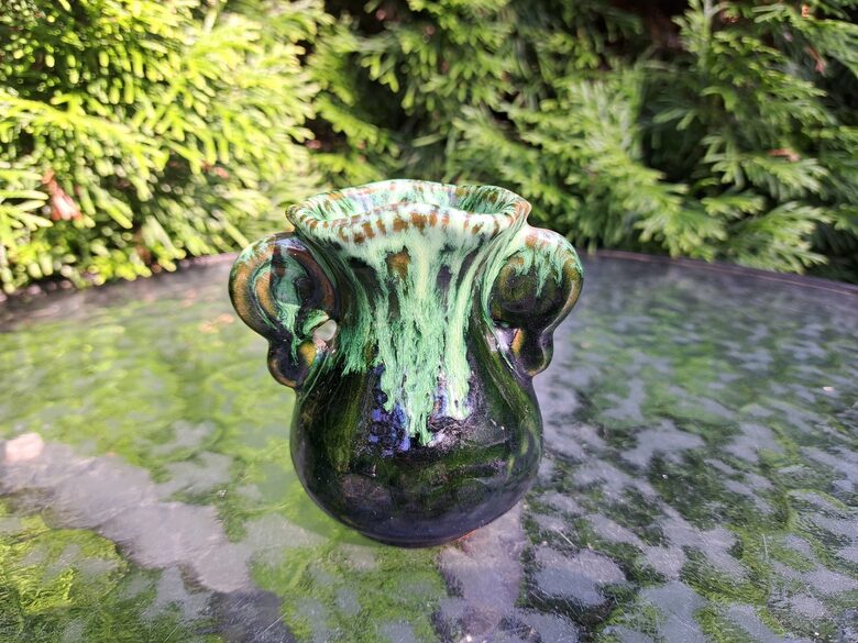 Māla mini vāzīte, viļņaina malas forma, tumši brūna ar zaļu. Roku darbs, glazūra. Augstums 8cm (Keram 141)