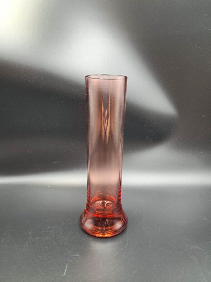 Rozā (tumšāks tonis) cilindriskā stikla vāze biezu un platu pamatni vienai puķei.  Augstums 20cm (Stikla vaze 180)