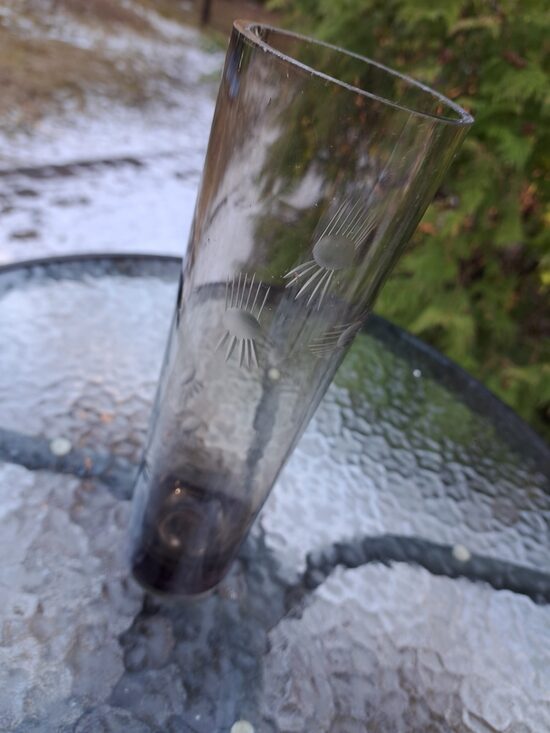 Brūngana (gaišāks tonis) cilindriskā stikla vāze ar smalku puķu grāvēšanu. Augstums 25,5cm, diam.7,5cm (Stikla vaze 151)