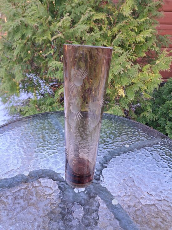 Brūngana (tumšāks tonis) cilindriskā stikla vāze ar smalku puķu grāvēšanu. Augstums 25,5cm, diam.7,5cm (Stikla vaze 150)