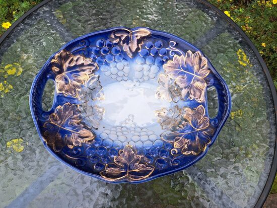 Grezna augļu bļoda ar reljefa rakstu - vīnogu ķekatiem, zilos toņos ar bagātīgu zeltu. Izmēri: 32cmx26,5cm (Korosten 66)