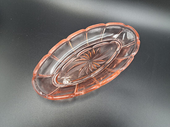 Izsmalcināts mazs garenais šķīvis, presēts maigi rozā stikls ar puķu motīviem. Izmēri: 16,5cm x 8cm; h=2,5cm.LORUP (Stikls sk 323)