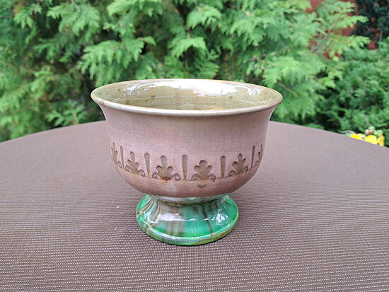 Plata māla vāzīte uz kājas ar 3 stobriņiem iekšā un tautīsku rakstu (spiedogi), krāsas pārēja no zaļas uz bēšāi. D=13,5cm; h=10,5cm (Keram vāze 71)