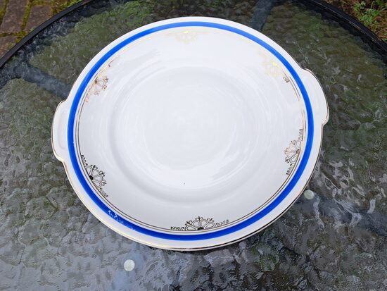 Vidējais servējamais šķīvis ar rokturiem d=27cm ar zilu malu un zelta tautīsku rakstu, pusdienu servīze "Gludā", PFF (Gludā 150)