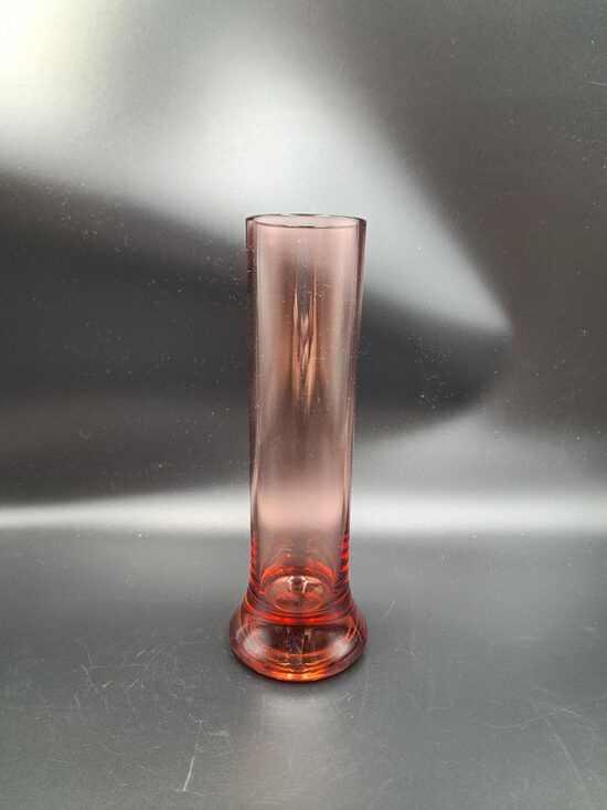 Rozā (tumšāks tonis) cilindriskā stikla vāze biezu un platu pamatni vienai puķei.  Augstums 20cm (Stikla vaze 180)