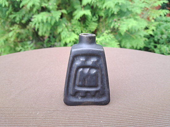 Mazā trapecveida vāzīte, reljefs raksts uz viena sāna, matēta glazūra, tumša brūna krāsa. Izmēri: 6cmx4,7cm, h=9cm (Keram vāze 73)