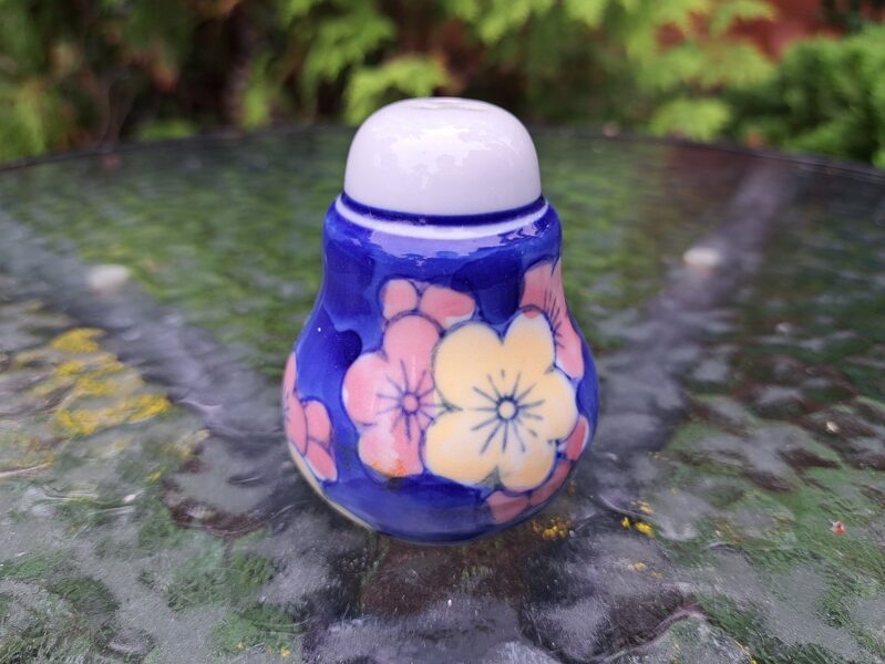 Skaists piparu trauks, rozā un dzeltenas puķes uz zila fona (Citi rpt 64)